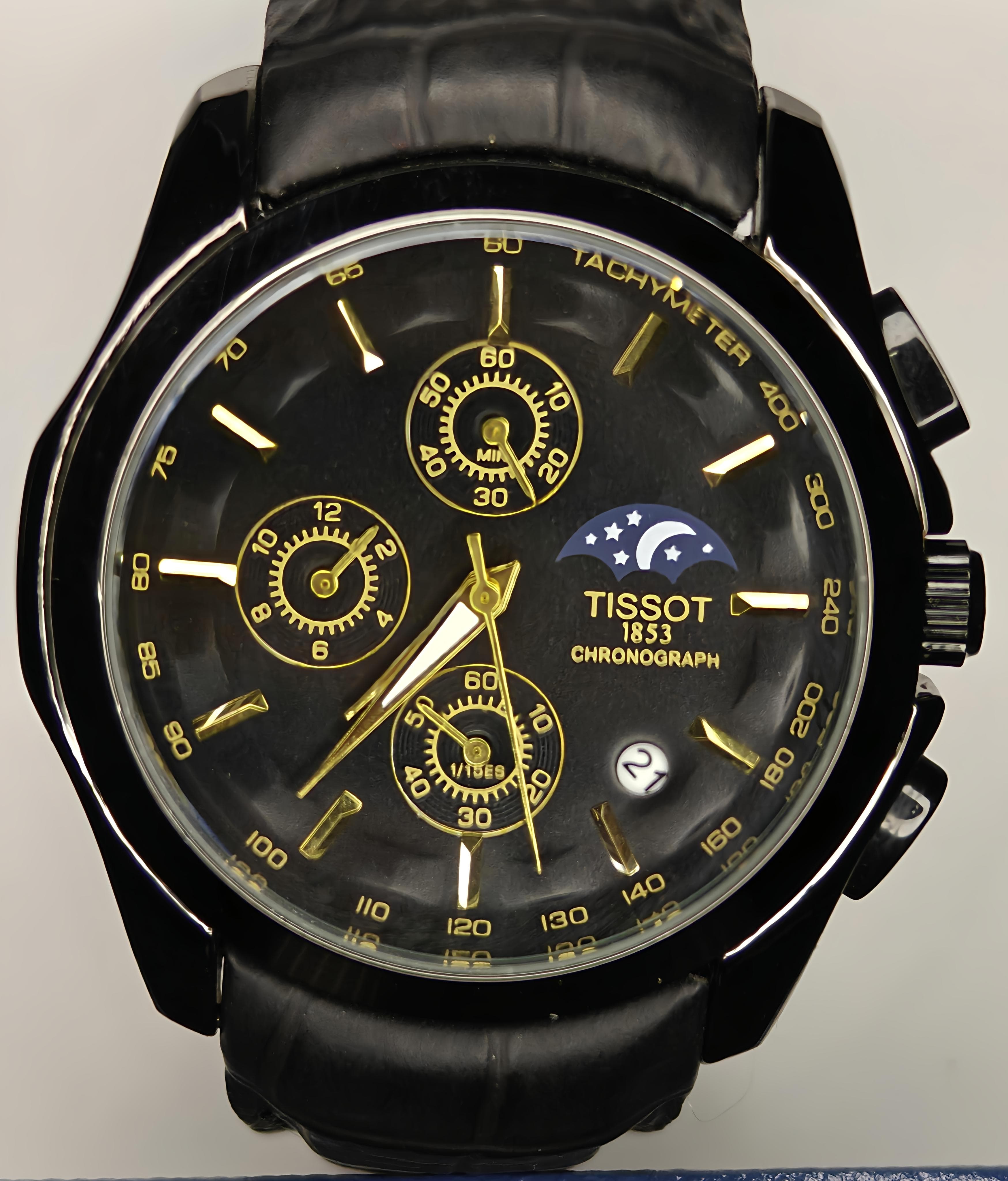Black Tissot watch with gold accents on a gray background